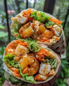 two wraps filled with shrimp and lettuce on top of each other in front of trees