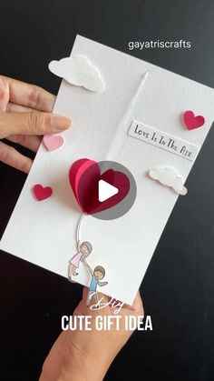 someone is holding up a card with hearts on it and the words love is in the air