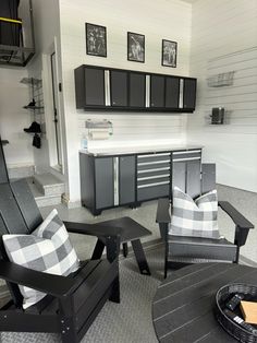 a living room filled with black furniture and lots of storage space next to a kitchen