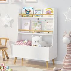 a stuffed giraffe sitting next to a white book shelf filled with books and toys