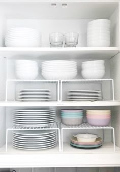 white dishes are stacked on shelves in the kitchen