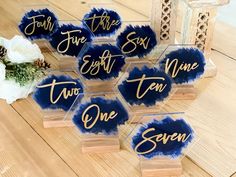 blue and gold acrylic name tags with white flowers on wooden table in background