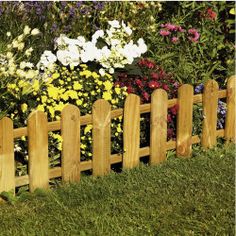 a wooden fence surrounded by flowers in the grass and on top of it is a flower bed