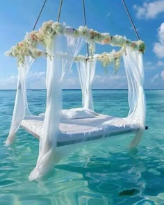 a bed in the ocean with flowers on it's head and some water around it