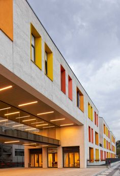 an empty parking lot next to a building with yellow and red shutters on the windows