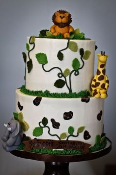 a three tiered cake with giraffes and elephants on it