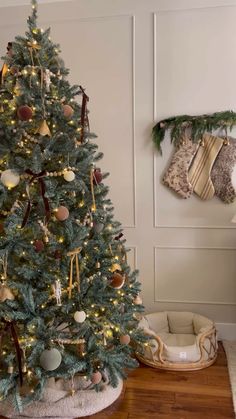 a decorated christmas tree with stockings hanging on the wall next to it and a dog bed