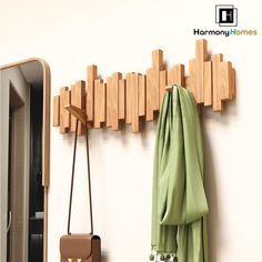 a coat rack and purse hanging on a wall next to a mirror with wooden pegs