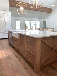 a large kitchen with an island in the middle and wood flooring on the other side