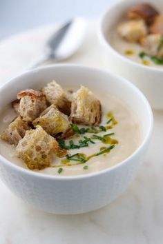 two white bowls filled with soup on top of a table