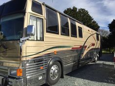 an rv parked on gravel with trees in the background