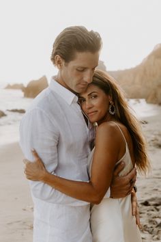 a man and woman embracing on the beach