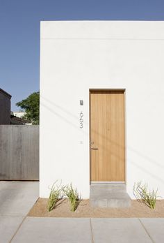 a white building with a wooden door and planters