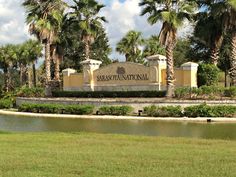 there is a sign in front of some palm trees and the name of the town