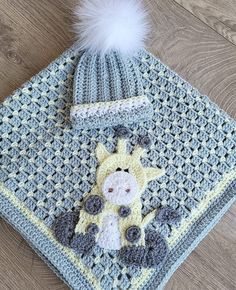 a crocheted baby blanket with a giraffe on it and a white pom - pom