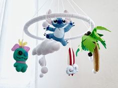 a mobile with stuffed animals hanging from it's sides and palm trees in the background