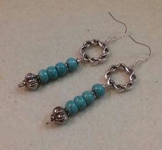 two pairs of earrings with turquoise beads and silver rings on them sitting on a white surface