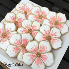 decorated cookies with pink flowers are on a white plate