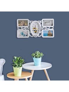 a white clock mounted to the side of a wall next to two potted plants