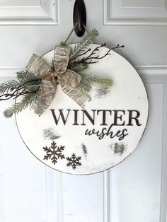 a sign that says winter wishes hanging on a door with snowflakes and evergreen branches