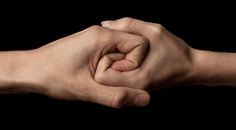 two hands holding each other in the middle of a fist bumping gesture on a black background