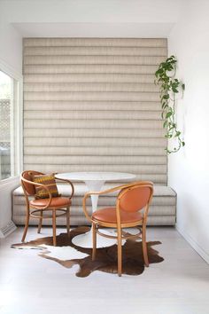 two chairs sitting at a table in front of a window with blinds on the wall