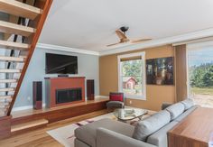 a living room with couches, coffee table and stairs leading up to the second floor