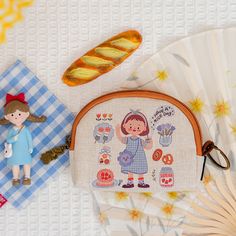 a small purse sitting on top of a table next to a doll and other items