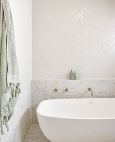 a white bath tub sitting in a bathroom next to a towel rack and toilet paper