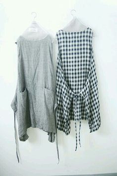 two pieces of clothing hanging on a wall next to each other, one in grey and the other in white