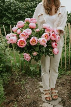 a woman holding a bouquet of pink flowers