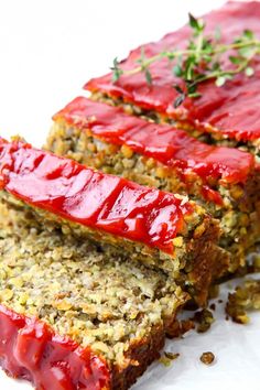 two slices of meatloaf with ketchup on top and sprigs of herbs