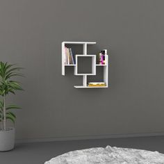 a white shelf with books on it next to a potted plant in a room