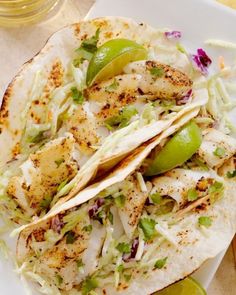 fish tacos on a plate with guacamole and salsa in the background