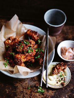 a plate full of fried food next to two bowls with chopsticks on the side