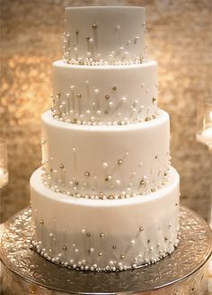 a three tiered white wedding cake with pearls on it