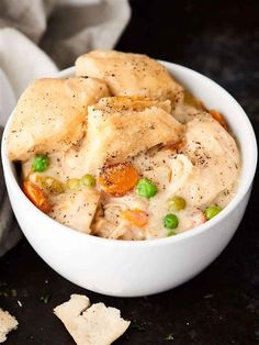 a white bowl filled with chicken pot pie and crackers on top of a table