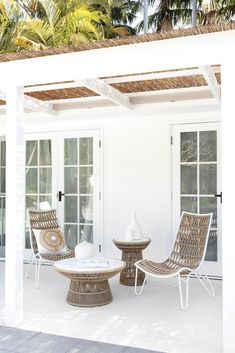 an outdoor patio with wicker furniture and palm trees