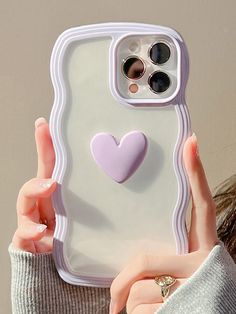 a woman holding up a phone case with a heart on it