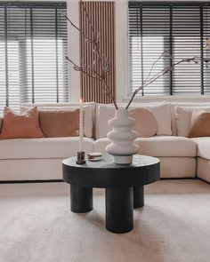 a living room filled with furniture and a tall vase on top of a coffee table