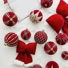 red and gold christmas ornaments are arranged on the snow with a white board in the background