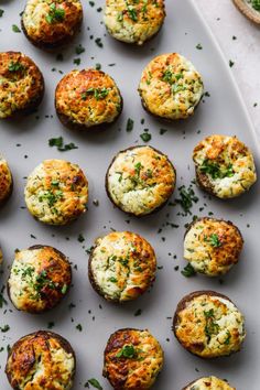 an overhead view of baked potatoes with cheese and herbs on a white platter, ready to be eaten