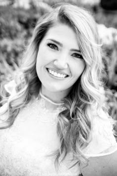 a black and white photo of a woman with long blonde hair smiling at the camera