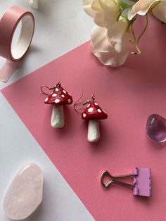 three little mushrooms sitting on top of a table next to some pink tape and flowers