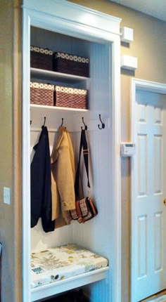 a white coat rack with coats hanging on it's hooks and two benches underneath