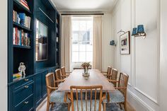 a dining room table with chairs and bookshelves in the corner, next to a blue bookcase