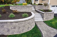 a retaining wall with steps leading up to it and landscaping in front of the house