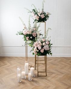 two gold stands with flowers and candles on the floor