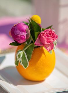 there is a small orange with flowers in it