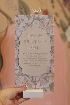 a person holding up a card with the words tuscani brusshetta table on it